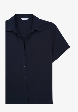 Chemise à manches courtes bleu marine foncé en tissu lisse, dotée d'une patte de boutonnage sur le devant et d'un col classique.