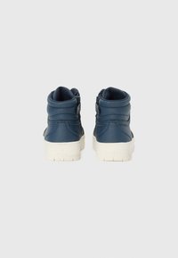 Høye sneakers i marineblå syntetisk materiale med hvite gummisåler. Har polstret krage og detalj med side-spenne.