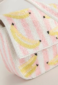 Petit sac à main décoré de rayures de perles roses et blanches ainsi que de motifs de bananes jaunes en perles, avec une anse perlée.