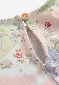Bomuldsskjorte med pastelfarver, der har blomster- og skovdyrtryk. Nøglehulsåbning ved halsudskæringen med en beige knapdetalje.