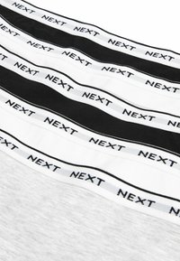 Set di cinque fasce elastiche in bianco e nero, con il marchio "NEXT" stampato sulla fascia. Tessuto morbido con una superficie liscia.