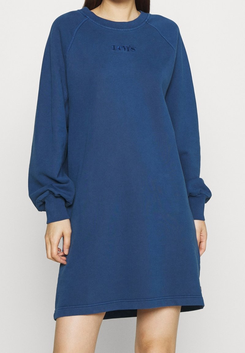 Blaues Sweatshirtkleid mit langen Ärmeln, Rundhalsausschnitt und Logodetail. Weicher Stoff mit lockerer Passform und gerippten Manschetten.