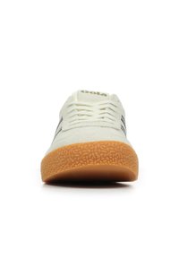 Sneaker bianco in suede con strisce nere, punta rotonda e suola in gomma a motivi. Presenta lacci e logo del marchio sulla linguetta.