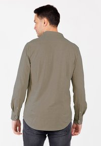 Camicia a maniche lunghe in tessuto verde oliva con yoke posteriore, orlo arrotondato e polsini con bottone. Texture liscia senza motivi.