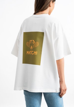 Weißes, übergroßes T-Shirt mit kurzen Ärmeln, das auf dem Rücken ein grünes rechteckiges Grafikdesign mit orangefarbenem Text und Illustrationen von Tennisschlägern zeigt.