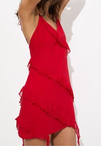 Rotes Chiffonkleid mit gestuften Rüschendetails, V-Ausschnitt und Spaghettiträgern. Verfügt über einen asymmetrischen Saum und eine leichte, fließende Textur.