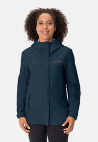 Giacca impermeabile blu navy con zip frontale, cappuccio e tasche laterali. Presenta una texture liscia e un logo arancione a contrasto sul petto.