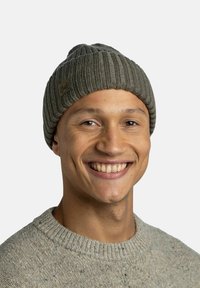 Knit beanie in gray with ribbed texture and turned-up brim; features a small brown label with "Buff" logo. Worn by a smiling individual.