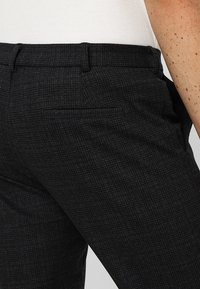 Donkergrijze gegoten broeken met een subtiel ruitenpatroon, slim fit ontwerp en een achterzakdetail.