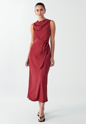 Red silk sleeveless dress with a draped neckline and waist tie; sleek, straight silhouette reaching mid-calf; smooth texture; minimalist design.
