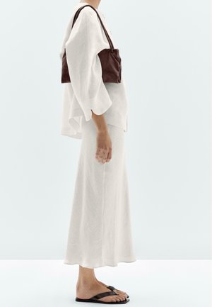 White linen top with wide sleeves paired with a long white skirt. Dark brown suede handbag and black flip-flops complete the outfit.