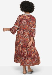 Vestido maxi en un patrón de paisley naranja y rojo, con mangas tres cuartos y acentos de encaje. Diseño fluido con una falda en capas.