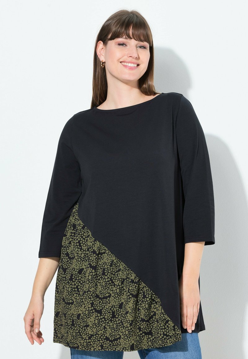 Tunic nera con maniche a 3/4, dotata di un pannello diagonale a motivo verde oliva. Tessuto morbido, vestibilità comoda, scollo rotondo.