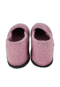 Pair of pink wool slippers with black soles, viewed from the back, showing soft fabric and rounded openings.