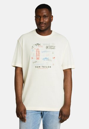 Homme portant un t-shirt crème avec une carte nautique et des illustrations de bateaux ainsi que le texte "Tom Tailor", associé à un jean bleu clair.