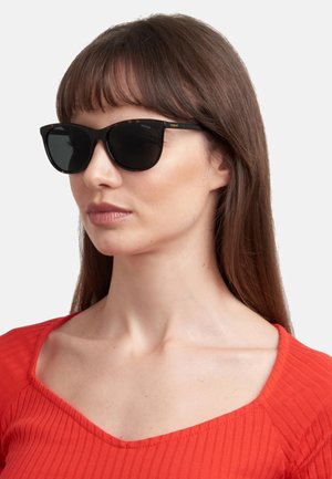 Occhiali da sole neri con finitura lucida e forma cat-eye leggermente arrotondata. Presentano un accento tartarugato sulle montature e lenti scure.