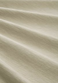 Beige stof met een gladde, licht gestructureerde oppervlakte, met subtiele horizontale lijnen en zachte plooien. Zacht, lichtgewicht en valt mooi.