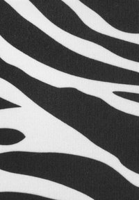 Schwarz-weißes Zebra-Streifenmuster auf einem strukturierten Stoff mit dünnen, gewellten Linien, die Kontrast und visuelles Interesse schaffen.