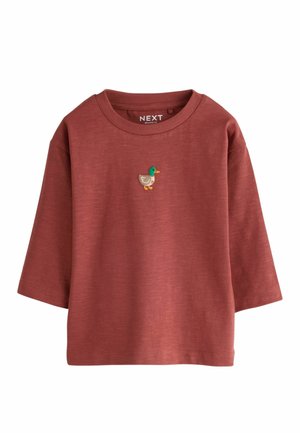 Rustfarvet langærmet skjorte med lille broderet and i grøn, gul og beige på brystet, mærket "NEXT Relaxed Fit" inden i kraven.