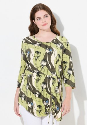 Groene bloemen tuniek met een ronde halslijn, driekwart mouwen en plooidetails aan de zoom. Heeft zwart-witte bloemenpatronen.