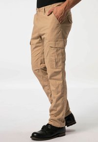 Beige Cargo-Hosen mit mehreren Taschen, aus leichtem Stoff. Verfügen über ein gerades Design, einen Knopfverschluss und werden mit schwarzen Stiefeln getragen.