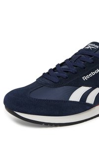 Granatowe sneakersy Reebok z białymi paskami, granatowymi sznurówkami oraz białą i czarną podeszwą, pokazane z boku.