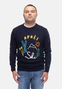 Granatowy sweter z kolorowymi, haftowanymi grafikami przedstawiającymi narty, góry, słońce i butelkę. Ribbowany dekolt i mankiety, luźny fason.