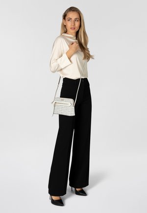 Cream satin blouse, high neckline, black wide-leg trousers, textured crossbody bag with logo pattern, black pointed heels, neutral background.
