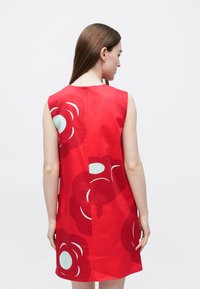 Červené šaty bez rukávov s veľkými kvetinovými vzormi v tmavočervenej a svetlomodrej farbe, so zatváraním na zips na chrbte a rovnou siluetou.