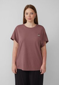 Kurze, locker sitzende T-Shirt in staubigem Rosa, aus weicher Baumwolle gefertigt. Verfügt über ein kleines gesticktes Design im linken Brustbereich.