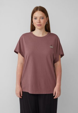 T-shirt à manches courtes, ample, en rose poussiéreux, fabriqué en coton doux. Présente un petit motif brodé sur le côté gauche de la poitrine.