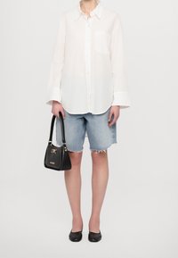 Vit långärmad skjorta med knappar, denimshorts, svart handväska med gulddetaljer och svarta ballerinas. En enkel, avslappnad outfit med en lös passform.