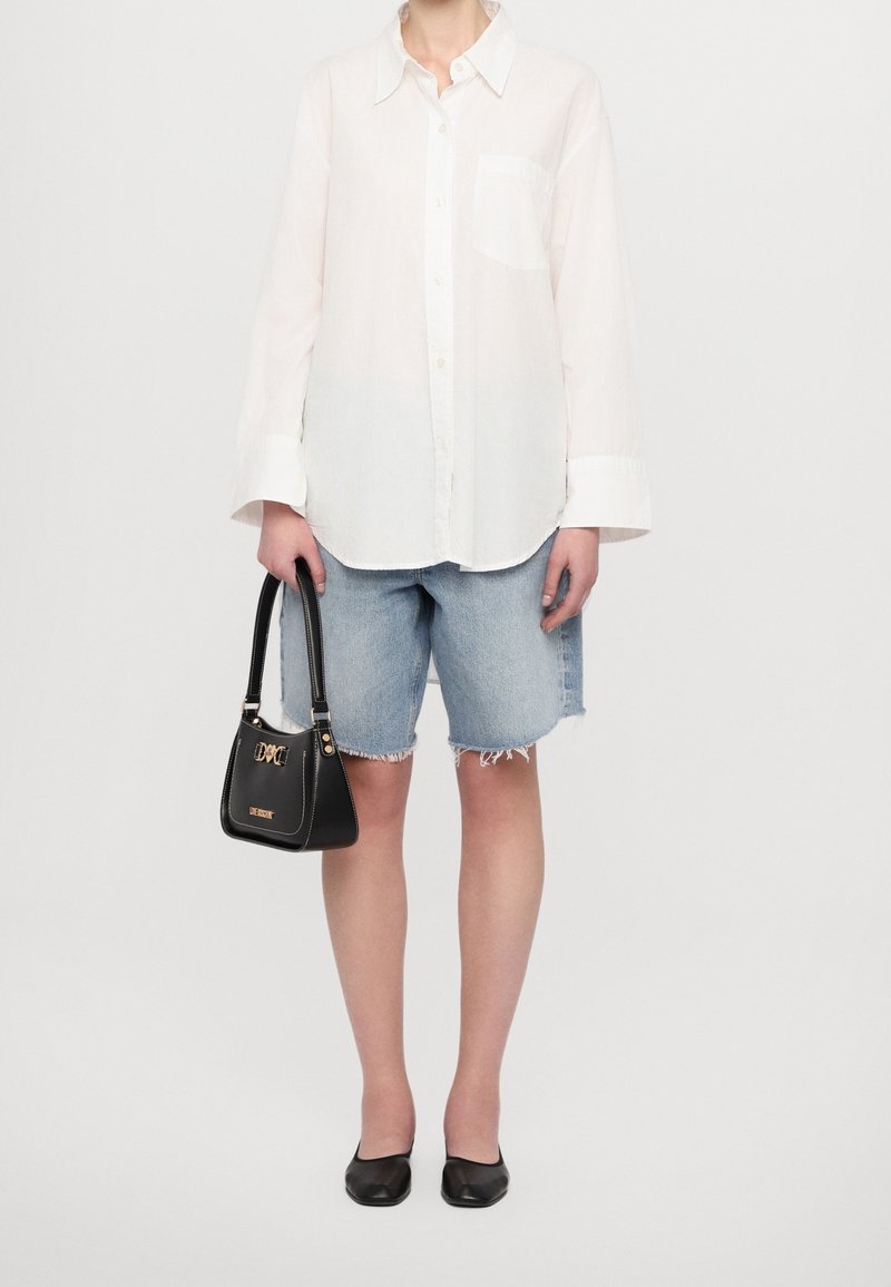 Vit långärmad skjorta med knappar, denimshorts, svart handväska med gulddetaljer och svarta ballerinas. En enkel, avslappnad outfit med en lös passform.