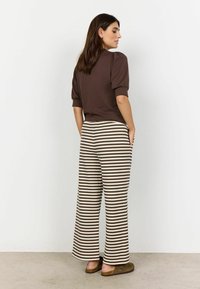 Brun kortærmet top og vide bukser med brune og creme striber. Blødt stof med en afslappet pasform. Flade sko fuldender outfittet.