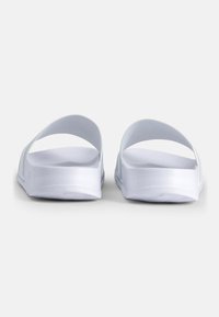 Sandales blanches à enfiler au design minimaliste, avec une finition lisse et brillante, des bords arrondis et des larges brides pour un confort optimal.