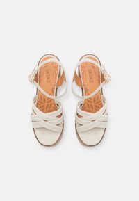 Sandali bianchi in suede sintetico con cinturini incrociati e una fibbia, dotati di una soletta imbottita color nocciola e un motivo floreale testurizzato.
