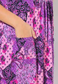 Mnohobarevné šaty s fialovými, růžovými a černými vzory. Obsahují boční kapsu, vyrobeny z měkké látky s volným designem.