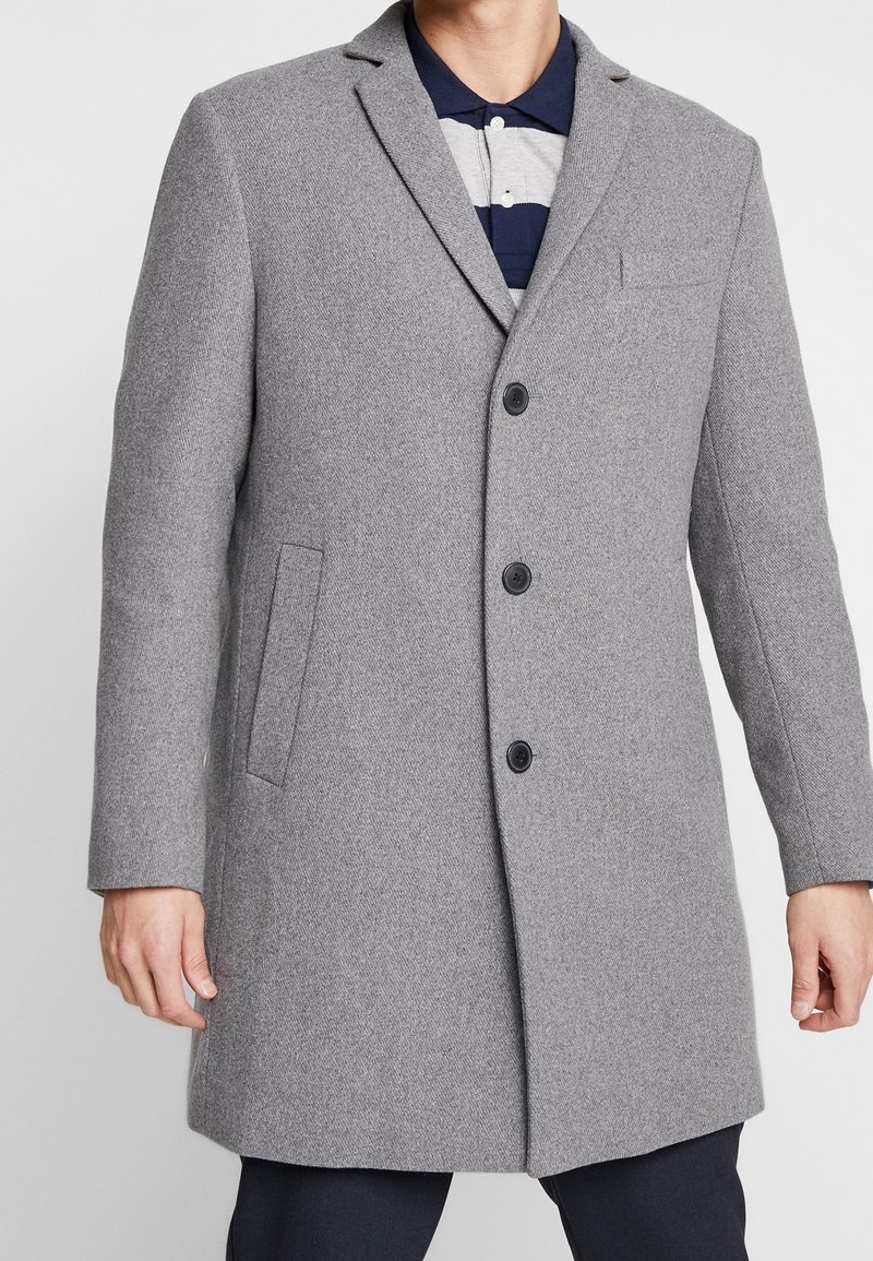 Cappotto grigio di lana con una texture liscia, due tasche laterali, rever a tacca e tre bottoni neri sul fronte.