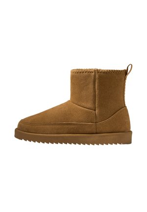 Stivaletto alla caviglia in camoscio marrone con suola piatta in gomma, dettagli cuciti sulla tomaia e linguetta sul retro per una facile calzata.
