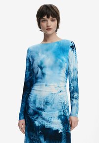 Plava haljina s dugim rukavima, s printom gradske scene u raznim nijansama plave, teksturirana tkanina i prilagođen silueta.