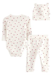 Ensemble pour bébé en trois pièces comprenant un body à manches longues et un pantalon, tous deux avec un fond blanc et des motifs de cœurs rouges, plus un bonnet assorti.