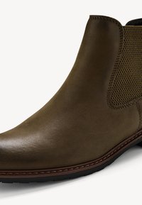 Botte de cheville en cuir marron foncé avec des panneaux latéraux texturés, bout rond et couture contrastante. Semelle en caoutchouc pour une traction.