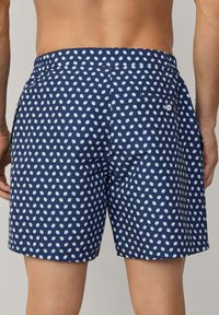 Blaue Badeshorts mit weißen Pünktchen, elastischem Bund und Seitentaschen. Verfügt über eine Gesäßtasche mit Knopfverschluss. Leichtes Material.