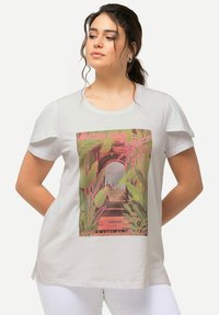 Maglietta grigia chiara con stampa grafica tropicale. Maniche corte, collo rotondo classico, spacchetti laterali, con dettagli vivaci in rosa e verde.