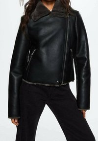 Veste en cuir noire avec un col en fausse fourrure grise douce, dotée d'une fermeture éclair et de poches latérales. La veste possède des manches longues et une coupe courte.