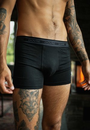 Schwarze Baumwoll-Boxershorts mit einem weichen Taillengummi, auf dem das "DOVRE"-Logo zu sehen ist. Eng anliegendes Design mit glatter Textur und minimalen Nähten.