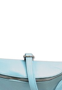 Helles blaues Lederhandtasche mit einer strukturierten Oberfläche, ausgestattet mit einem Reißverschluss und einem verstellbaren Riemen. Glatte Kanten und silberne Hardware-Akzente.