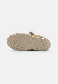 Baskets beiges avec une tige en tissu texturé. Semelle en caoutchouc blanc avec un motif de rainure. Détail de nœud décoratif sur le dessus.