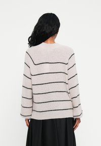 Helles rosa, übergroßes Sweatshirt mit schwarzen horizontalen Streifen, langen Ärmeln und rundem Halsausschnitt, hergestellt aus weichem, strukturiertem Stoff.