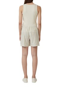 Beige, geripptes Tanktop kombiniert mit hell gestreiften Shorts. Die Shorts haben einen elastischen Bund und zwei Gesäßtaschen. Lässige Schuhe vervollständigen das Outfit.